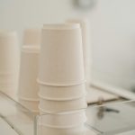 Set of various white paper cups placed on coffee machine in modern cafe